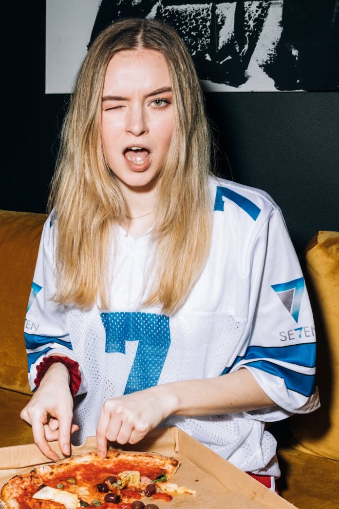 young woman winking while getting a slice of pizza