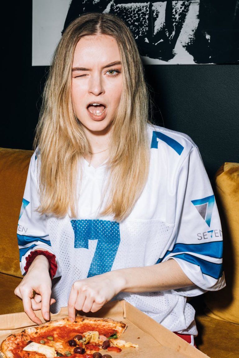 young woman winking while getting a slice of pizza